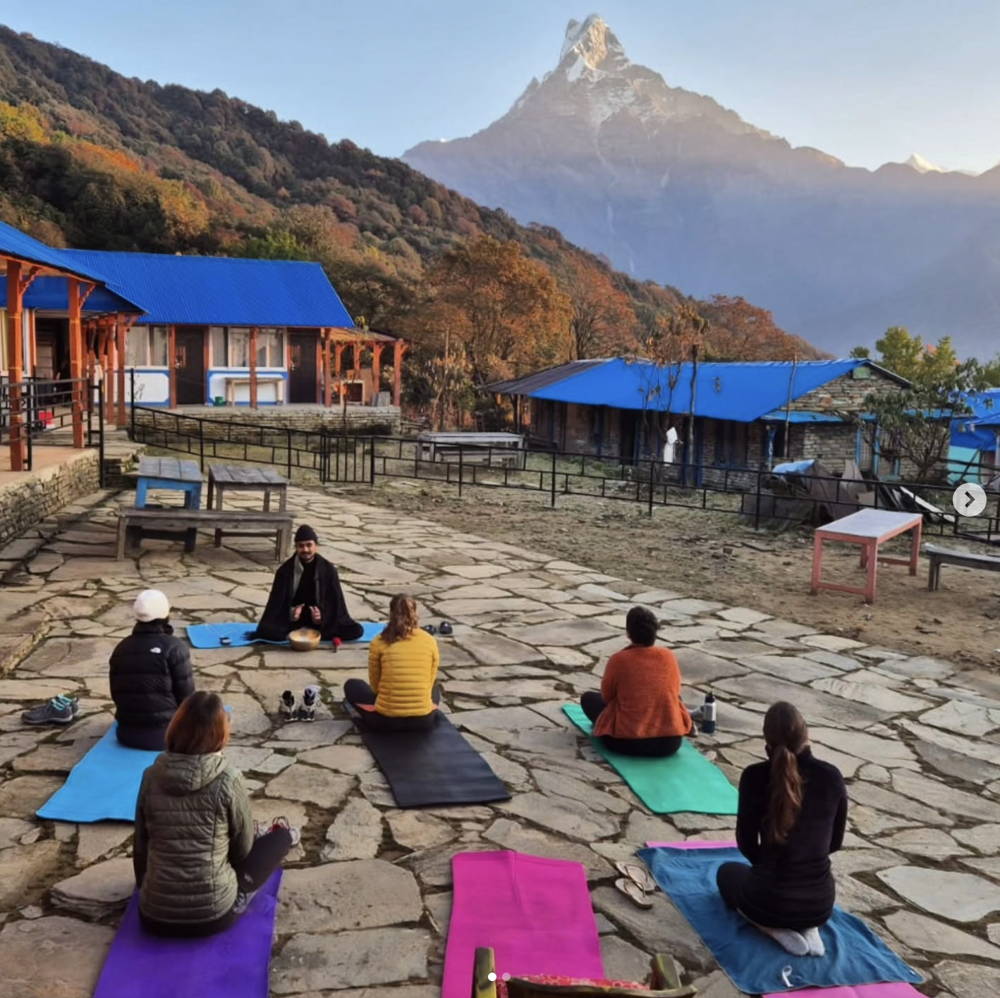 Group yoga class on colorful mats with Mardi Himal peak
