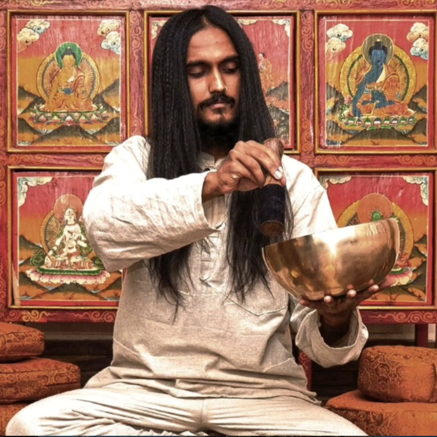 Sound healing with singing bowl in front of Buddhist thangka paintings