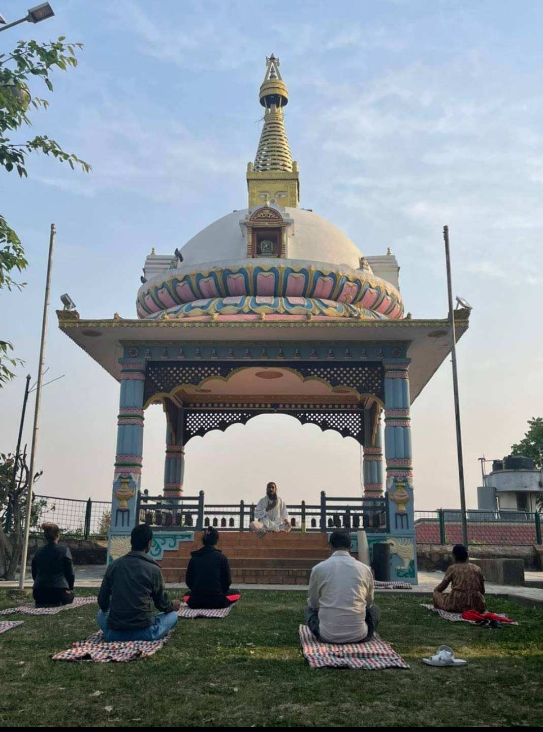 Group meditation in front of golden Buddhist stupa